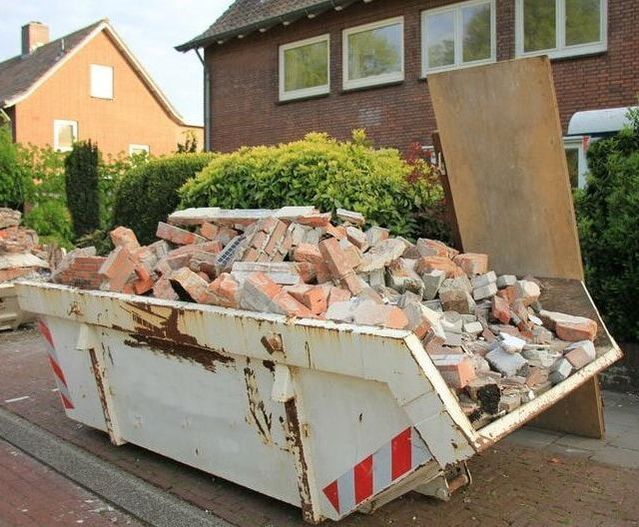 A 10 yard commercial container being used to dispose of bricks