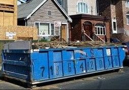 large construction dumpster placed outside of a home during a renovation project